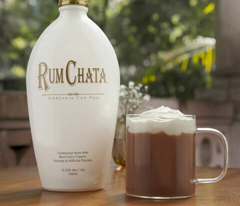 A glass cup of chococoffee and a bottle of Rumchata on a wooden table