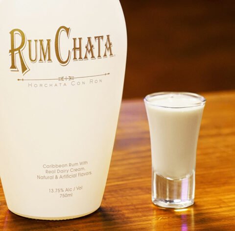 A shot of coco-chata and a bottle of Rumchata on a wooden table