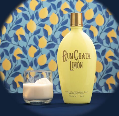 A glass of Rumchata limon and a bottle of Rumchata Limon in front of a blue leaves and lemon wallpaper