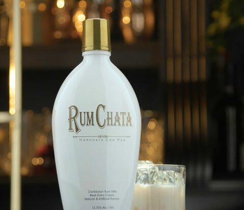 Un verre de peche et creme et une bouteille de rumchata