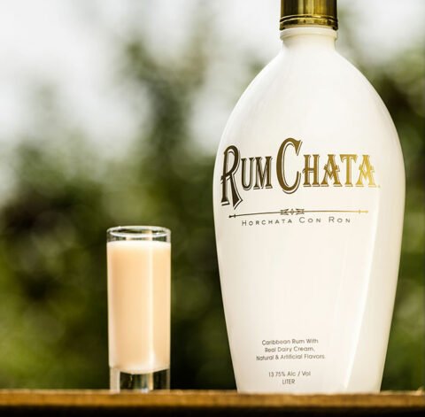 A shot of pie hard and a bottle of Rumchata outside on a wooden table