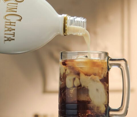 Une bouteille de rumchata se deversant dans un bock a biere de root beer