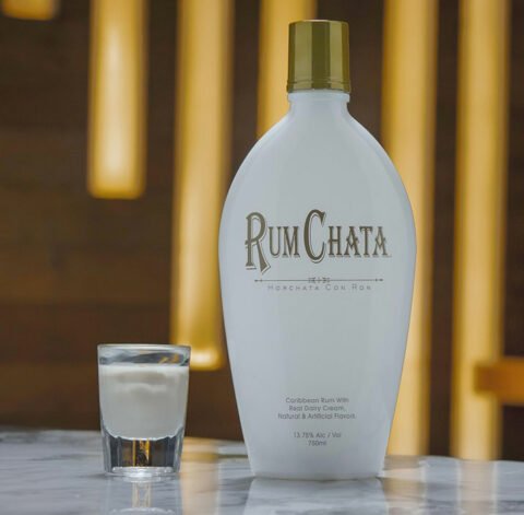 A shot of Rumchata and a bottle of Rumchata on a marble table