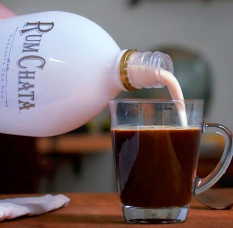 Quelqu'un deversant du rumchata dans un verre de cafe maya epice