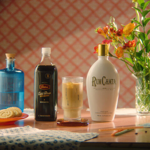 A glass of Mexican Cold Brew between a bottle of Rumchata and a bottle of Cold Brew coffee concentrate.